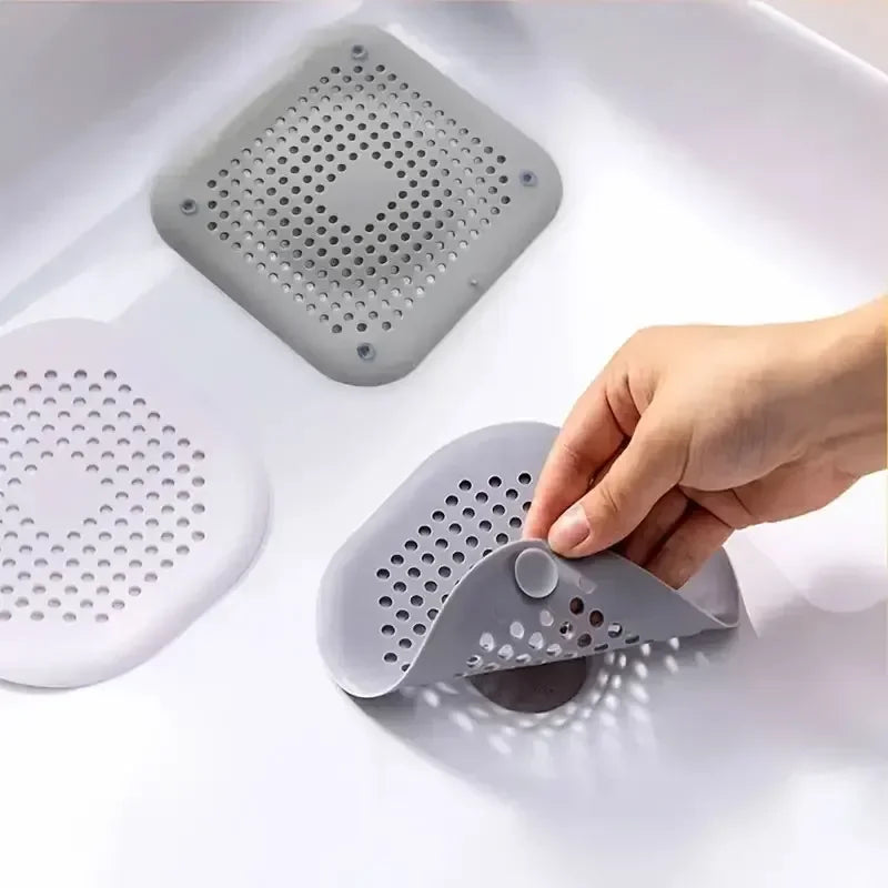 Gray silicone sink strainer being held over a white