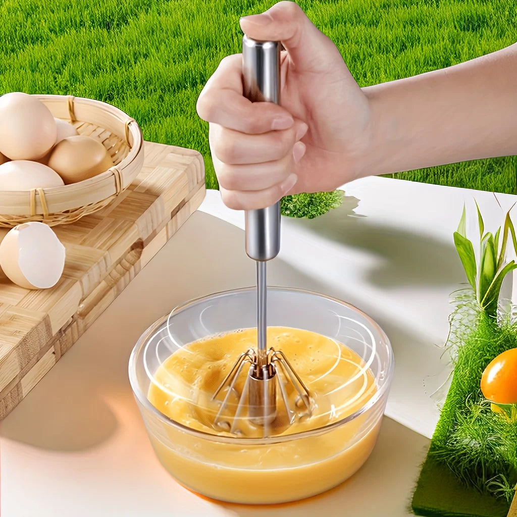 Stainless steel egg whisk mixing eggs in a bowl outdoors 