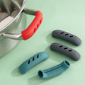 Silicone pan handle covers in multiple colors beside a saucepan 