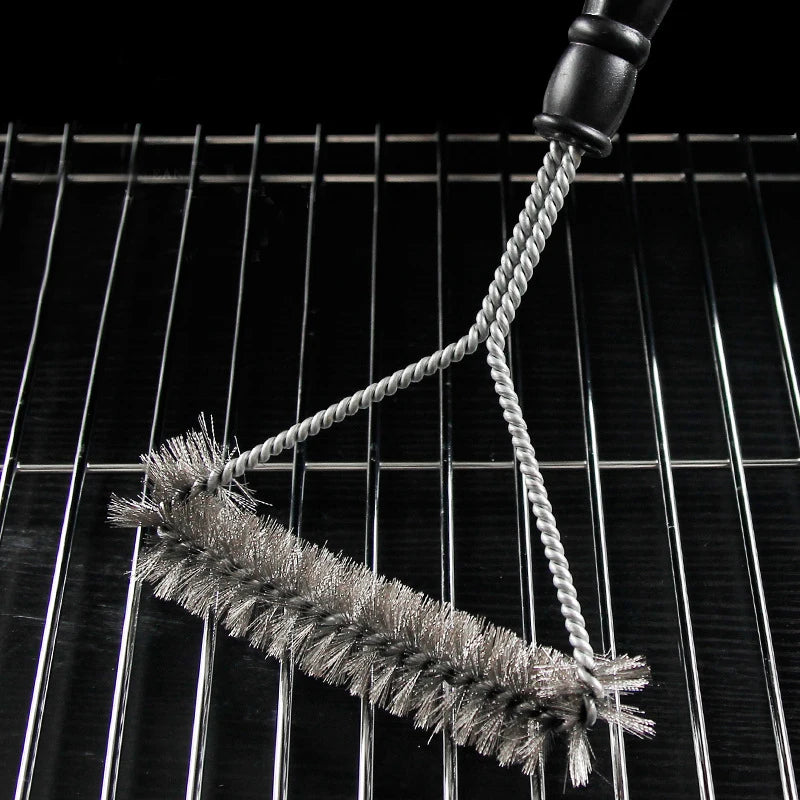 Grill cleaning brush resting on barbecue grill grates 