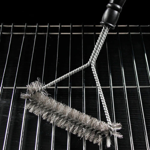 Grill cleaning brush resting on barbecue grill grates 